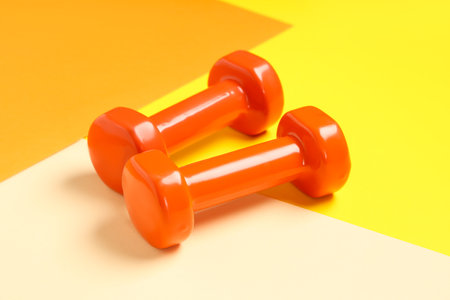 Orange dumbbells on color backgroundの写真素材