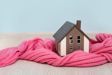 Decorative house with scarf near blue wall. Winter heating conceptの写真素材