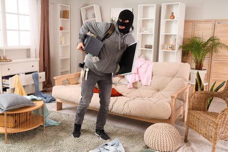 Male thief stealing safe and monitor in room