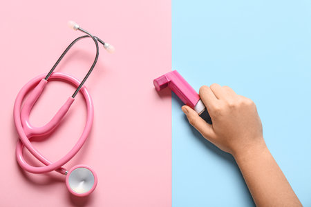 Child's hand with asthma inhaler and stethoscope on color backgroundの写真素材