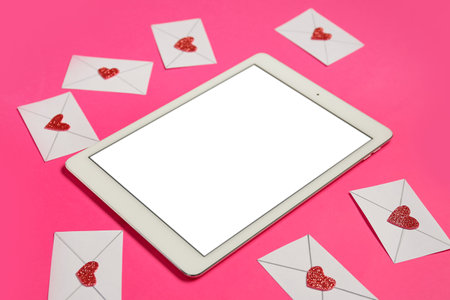 Tablet computer with love letters on pink background. Concept of online datingの写真素材