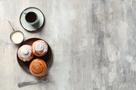 Plate with cinnamon buns, cream and cup of coffee on gray grunge backgroundの写真素材