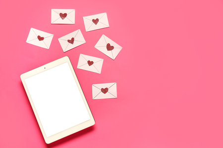 Tablet computer with love letters on pink background. Concept of online datingの写真素材