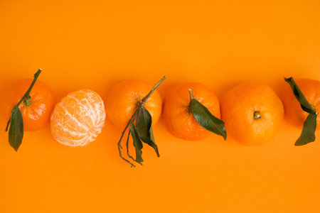 Tasty tangerines with leaves on orange backgroundの写真素材