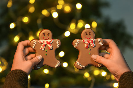 Female hands with sweet Christmas cookies on against blurred lights, closeup