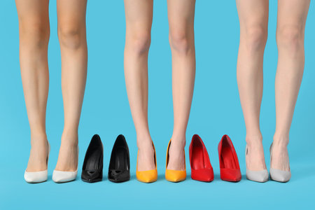 Female legs wearing different shoes on blue backgroundの写真素材