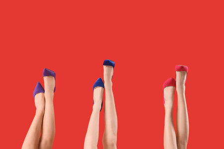 Female legs wearing different shoes on red backgroundの写真素材
