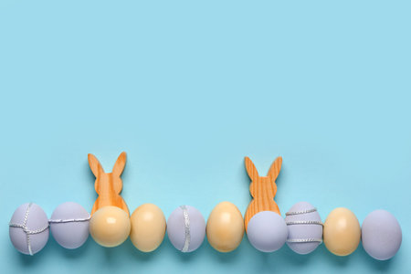 Painted Easter eggs with wooden bunnies on blue background