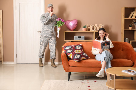 Man in military uniform with bouquet of flowers sneaking to surprise his wife at home. Valentine's Day celebrationの写真素材