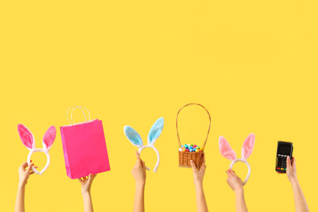 Women with bunny ears, Easter eggs and payment terminal on yellow background. Online shoppingの写真素材