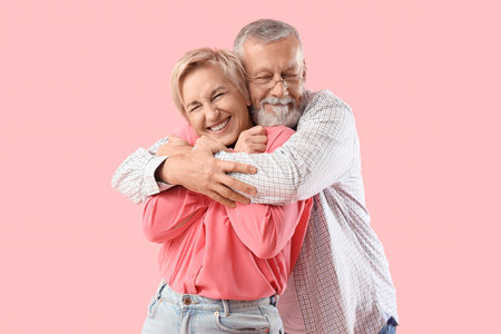 Mature couple hugging on pink backgroundの写真素材