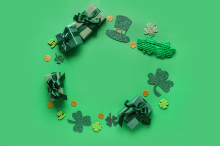 Frame made of gift boxes with clovers and golden coins for St. Patrick's Day celebration on green backgroundの写真素材
