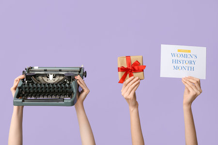 Female hands with retro typewriter, gift and greeting card for International Women's Day on lilac background, closeupの写真素材