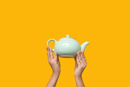 Woman with ceramic teapot on yellow backgroundの写真素材