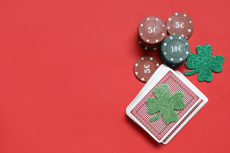 Poker chips, deck of cards and lucky clovers on red background. St. Patrick's Day celebrationの写真素材