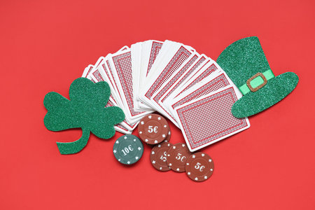 Poker chips with cards and lucky clover on red background. St. Patrick's Day celebration