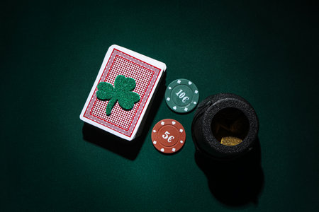 Poker chips, cards, pot with coins and lucky clover on dark green background. St. Patrick's Day celebrationの写真素材