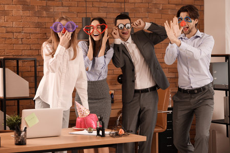 Business colleagues with funny disguise grimacing in office. April Fools' Day celebrationの写真素材
