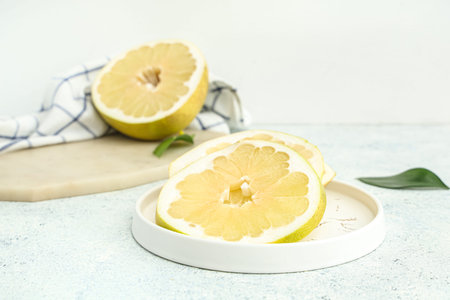 Plate with slices of fresh pomelo fruit on white background