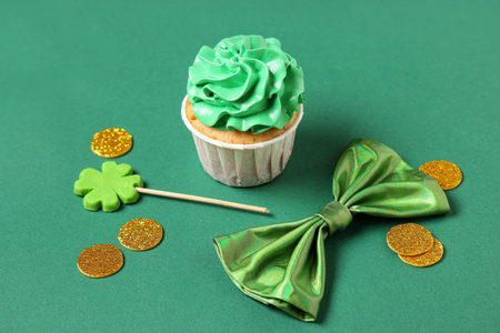 Tasty cupcake with bow tie and decor for St. Patrick's Day on green backgroundの写真素材