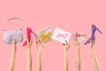 Female hands with gift boxes, high heel shoes and festive postcard on pink background. Shopping for International Women's Dayの写真素材