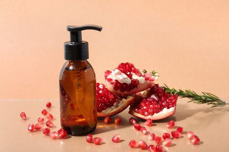 Bottle of cosmetic product, ripe pomegranate and rosemary on color backgroundの写真素材