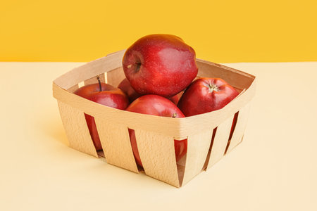 Basket with fresh red apples on colorful backgroundの写真素材