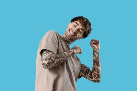 Young tattooed man dancing against blue backgroundの写真素材