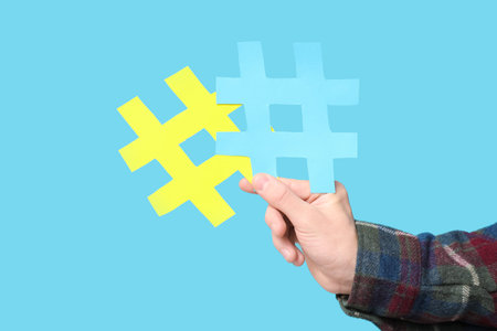 Hand of young man with hashtag symbols on blue background