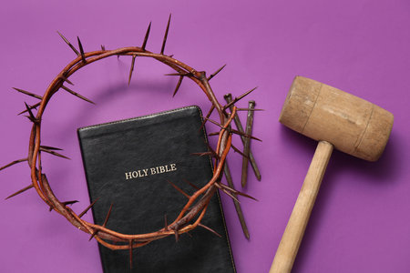 Crown of thorns with Bible, hammer and nails on purple background