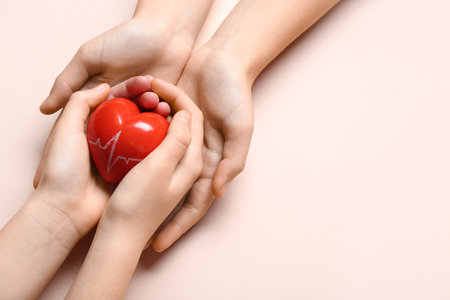 Hands of woman and child holding red heart on pink backgroundの写真素材