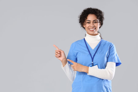 Female African-American medical intern pointing at something on light backgroundの写真素材