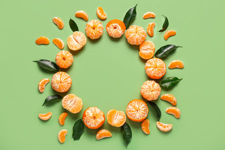 Frame made of sweet tangerines and leaves on green backgroundの写真素材