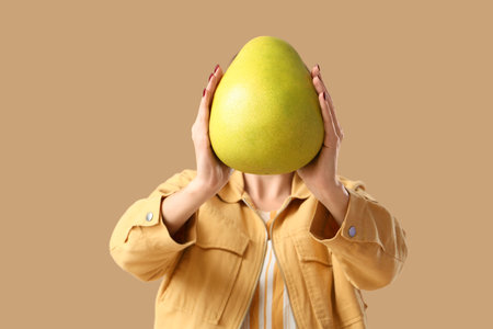 Young woman with pomelo on brown background, closeupの写真素材