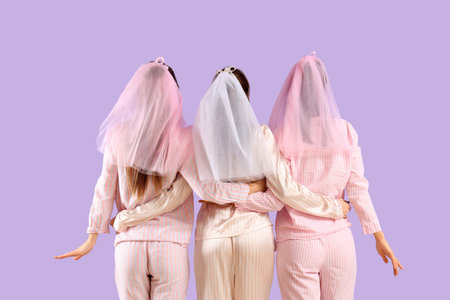 Young woman with her bridesmaids in pajamas hugging on lilac background, back view. Hen Partyの写真素材