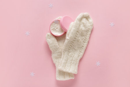 Jar of cream with snowflakes and warm winter gloves on pink backgroundの写真素材