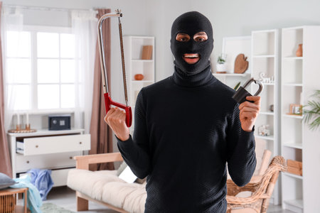 Male thief with hacksaw and broken lock in room