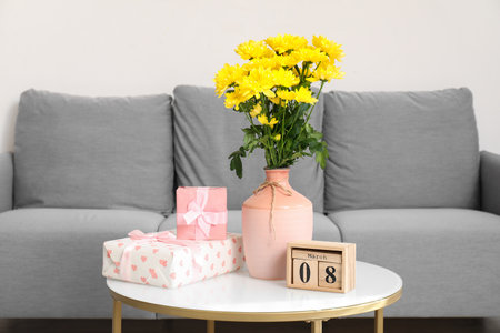 Vase with yellow flowers, calendar and gifts on coffee table in living room. International Women's Day celebrationの写真素材