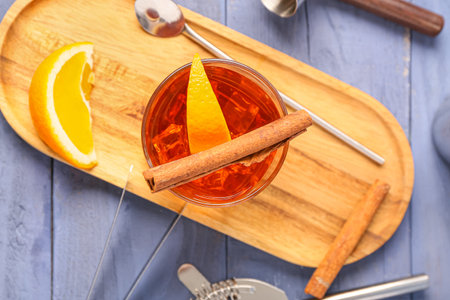 Board with glass of delicious Old Fashioned Cocktail and orange slices on blue wooden backgroundの写真素材