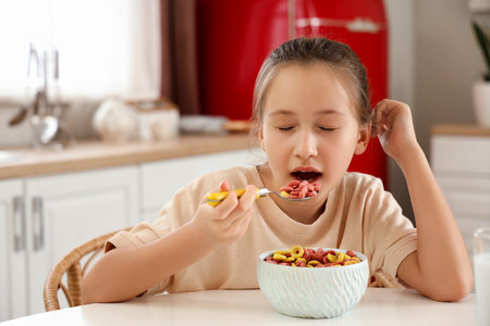 Cute little girl eating cereal rings at homeの写真素材