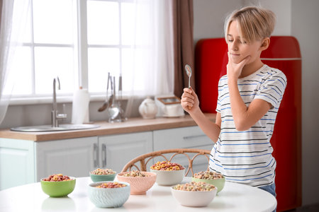 Thoughtful little boy with cereal rings at homeの写真素材