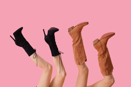 Female legs wearing stylish boots on pink backgroundの写真素材