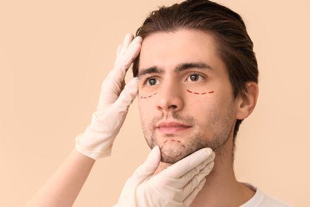 Plastic surgeon and young man with marked face on beige background, closeupの写真素材