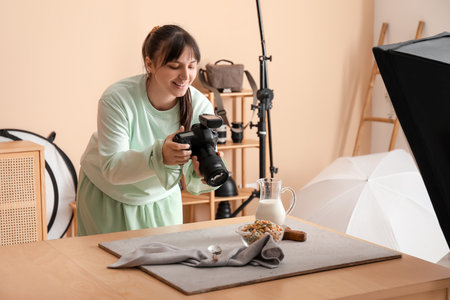 Female food photographer taking picture of tasty cereal rings with milk in studioの写真素材