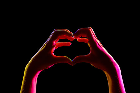 Silhouette of woman making heart gesture on dark background, closeupの写真素材
