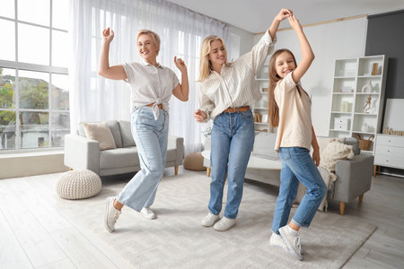 Little girl with her mom and grandmother dancing at homeの写真素材