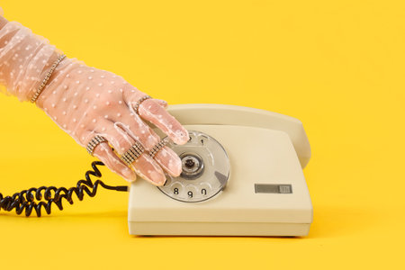 Woman with silver jewelry and telephone on yellow background, closeupの写真素材