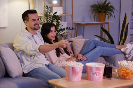Young couple watching TV at home in eveningの写真素材