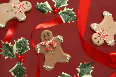 Sweet gingerbread cookies with Christmas decor on red background.