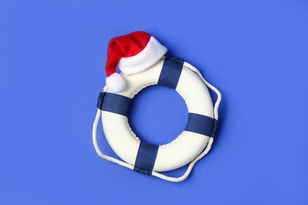 Lifebuoy ring with Santa hat on color backgroundの写真素材